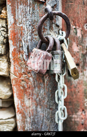 Vintage Corroded Padlocks  with Chain on a Ancient Red Gate Background. Old Rusty Padlocks on a Wooden Door. Stock Photo