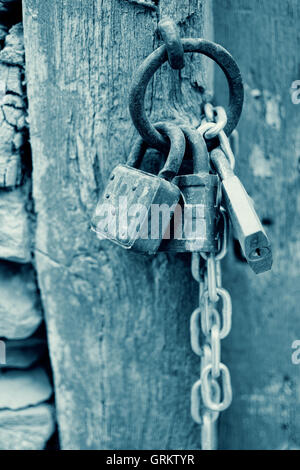 Vintage Corroded Padlocks  with Chain on a Ancient Gate Background in Cyan. Old Rusty Padlocks on a Wooden Door. Stock Photo