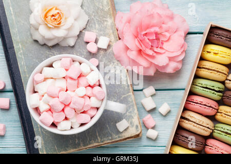 Colorful macaroons and marshmallow on wooden table. Sweet macarons in gift box. Top view Stock Photo