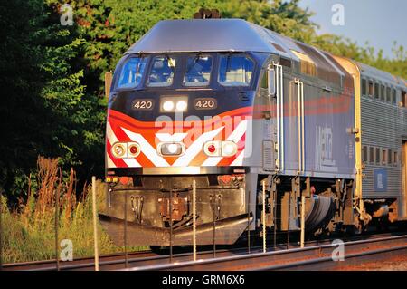 A Metra commuter train thundering through Bartlett, Illinois on a line connecting Chicago with Elgin, Illinois. USA. Stock Photo