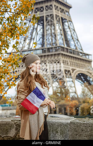 Autumn getaways in Paris. happy young elegant woman on embankment near Eiffel tower in Paris, France with flag Stock Photo