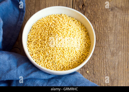 organic millet in ceramic bowl on wooden rustic table close up Stock Photo