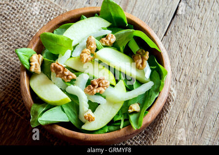 Waldorf salad with green apple, celery and walnuts in wooden bowl over rustic background Stock Photo