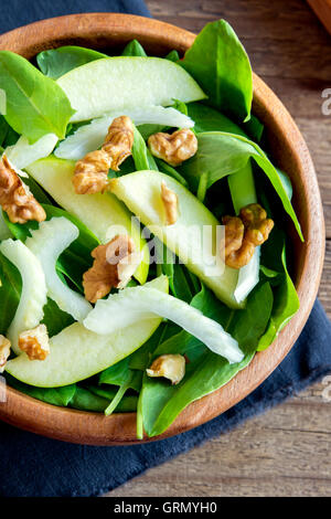 Waldorf salad with green apple, celery and walnuts in wooden bowl over rustic background Stock Photo