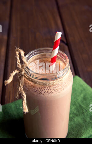 Chocolate smoothie (milkshake) with straw in jar on dark wooden table Stock Photo