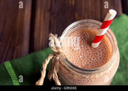 Chocolate smoothie (milkshake) with straw in jar on dark wooden table Stock Photo