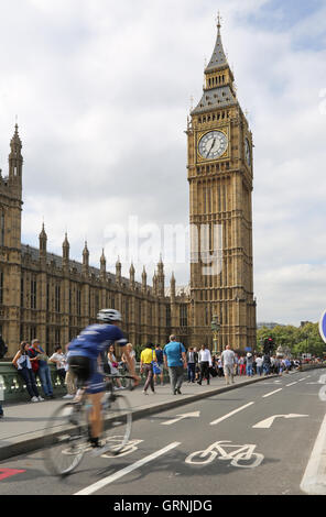 A cyclist (blurred through speed) on London's new cycle path on Westminster Bridge passes Big Ben and the Houses of Parliament. Stock Photo
