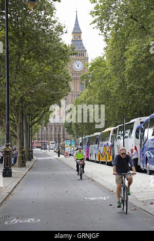 Cyclists use London's new segregated cycle path on Victoria Embankment, next to the River Thames. Big Ben in the background. Stock Photo