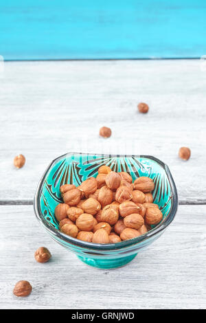 Hazelnuts in a green bowl on a rustic table, space for text. Stock Photo