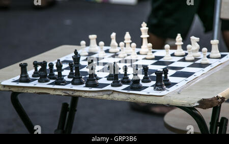 A chessboard on a worn out folding table with all the pieces set for the start of game. Stock Photo