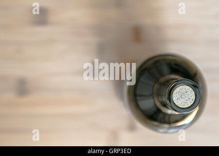 A still life with a wine bottle standing on a wooden surface blurred background, view from above. Stock Photo