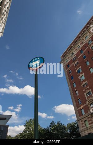 A city bus stop pole near residential buildings against blue sky. Stock Photo