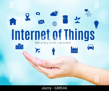 Open hand with Internet of Things (IoT) word and icon on blue blur background, Technology concept. Stock Photo