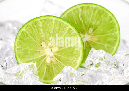 Cut lime (Citrus aurantifolia (Christm.)  Swingle) and ice on white Background. Stock Photo