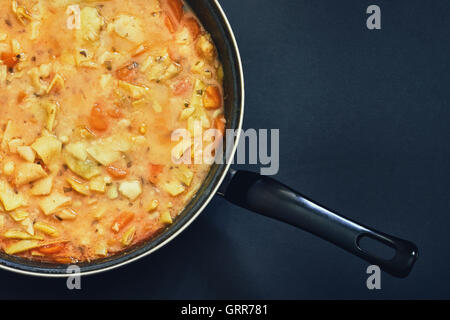 Cooked vegan green beans stew in black pan on dark background. Top view with copy space Stock Photo