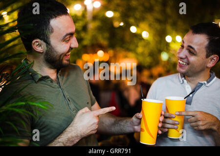 Two young cheerful male friends at street or park party outdoors Stock Photo