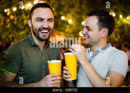 Alcoholics people drinking and having fun at outdoors cafe or park. Smiling couple alcohol friendship concept. Stock Photo