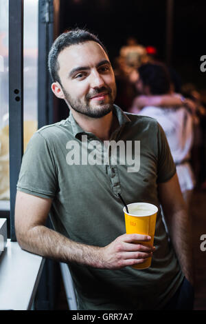 Handsome Bearded European Man Drinking coctail or beer at outdoor Street Cafe night party in park Stock Photo