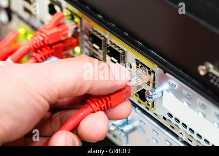 Hand Plugging Network Cable Into Switch In Datacenter Stock Photo