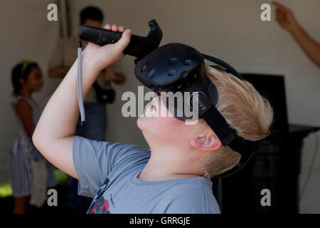Child wearing VR headset (VR goggles) using bluetooth controller - USA Stock Photo