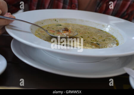 Woman's hand with the spoon while eating soup in the restaurant Stock Photo