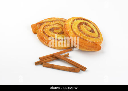 sweet cinnamon rolls and cinnamon sticks on white background Stock Photo