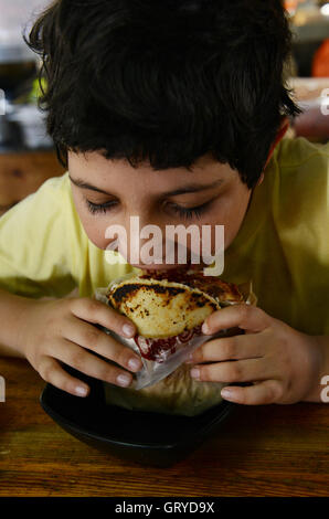 A boy eating Arepa con Carne ( Arepa with meat ). Stock Photo