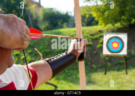 Medieval archer to use a bow and arrow and shoot at a target Stock Photo