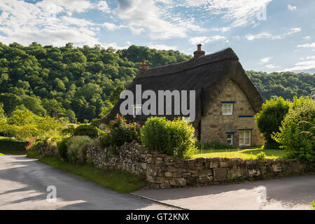 Sunny, evening view along a quiet country lane, passing a thatched cottage in pretty Rievaulx Village, North Yorkshire, England. Stock Photo