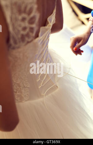 Bridesmaid tying bow on wedding dress Stock Photo