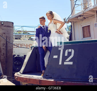 Couple in wedding attire with a bouquet of flowers on the boat Stock Photo