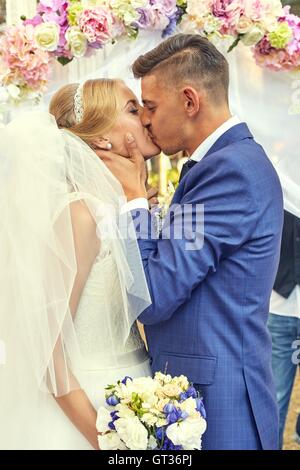 Newlyweds under ceremony arch in beautiful spring day Stock Photo