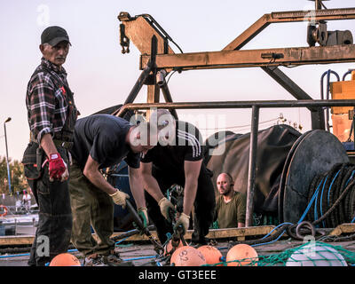 Fishermen working with fishnet at the harbor Stock Photo
