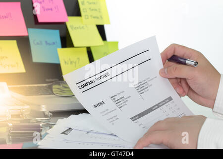Businessman review his company invoice on tangle office desk for made a payment. Stock Photo