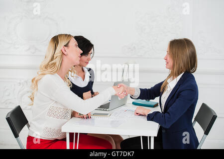 Two Businesswomen Shaking Hands In Modern Office Stock Photo