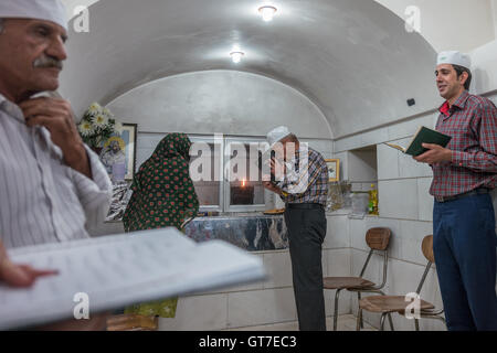 Worshippers with the Khordeh Avesta prayer book before the Atash Bahram, meaning “Victorious Fire”, dated to 470 AD  with Zoroastrian symbols. Stock Photo