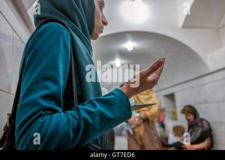 Young woman worships before the Atash Bahram, meaning “Victorious Fire”, dated to 470 AD  with Zoroastrian symbols. Stock Photo