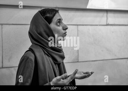 Young Iranian woman worships before the Atash Bahram, meaning “Victorious Fire”, dated to 470 AD  with Zoroastrian symbols. Stock Photo