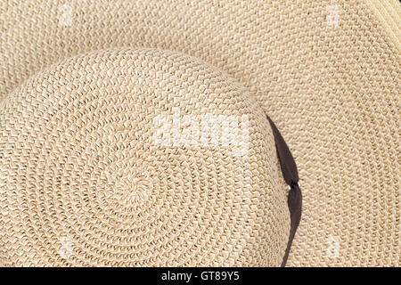Background texture of a straw sunhat viewed from above showing the pattern of the weave on the crown and brim Stock Photo