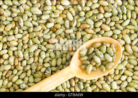 Background food texture of dried edamame, or green soya beans, with a wooden spoon placed diagonally on the surface, full frame Stock Photo