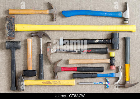 Large selection of different hammers and mallets arranged on a neutral beige background viewed from above in a DIY, renovation, Stock Photo