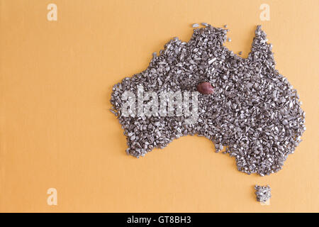 Conceptual map outline of Australia and Tasmania formed from an arrangement of silvery stone chips and fragments on yellow Stock Photo