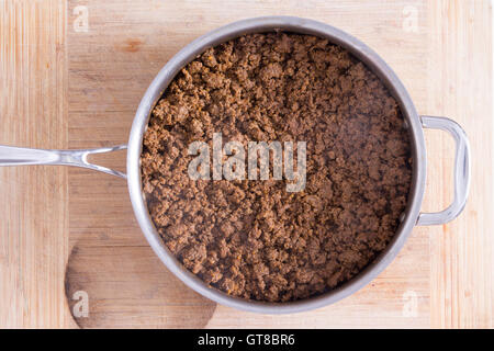 Close up Big Pan with Smoking Hot Ground Beef on Top of a Wooden Cutting Board, Captured in High Angle View. Stock Photo