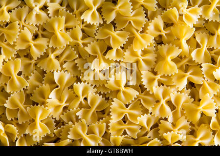 Full frame background of decorative dried Italian bow tie pasta resembling butterflies in flight in a close up overhead view Stock Photo