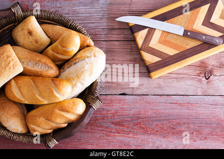 Assorted fresh rolls in a basket ready to be served for dinner standing on a rustic wooden table alongside a decorative inlaid Stock Photo