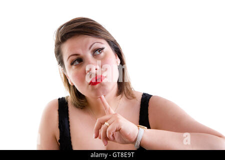 Attractive middle-aged woman deep in thought staring pensively up into the air with her finger to her chin as she makes her deci Stock Photo