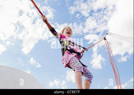 6 year old girl jumping with a bungee trampoline on a sunny day, Germany Stock Photo
