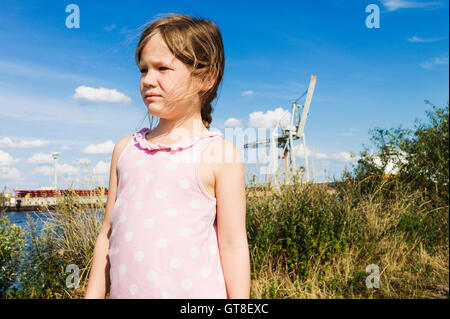 5 year old girl standing in a field near a harbor on a sunny day, Germany Stock Photo