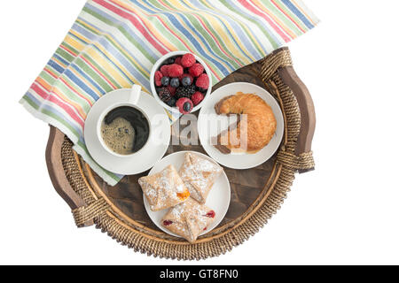 Tasty morning breakfast on a wicker tray with freshly baked pastries filled with cheese, strawberry and peach, a croissant with Stock Photo