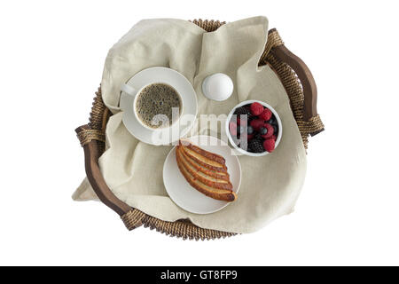 Tasty breakfast for one on a rustic wicker tray with a cup of fresh espresso coffee, boiled egg, ramekin of fresh assorted berri Stock Photo